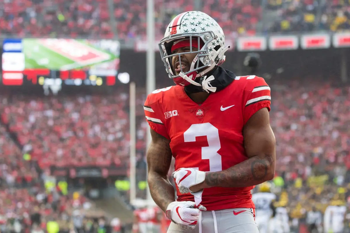 Ohio State cornerback Damon Arnette, number 3 in scarlet, adjusting his gloves on the field with the stands of Ohio Stadium full behind him