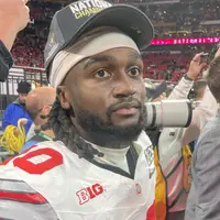Denzel Burke in a white Ohio State jersey and a National Champions cap on the field after the championship game
