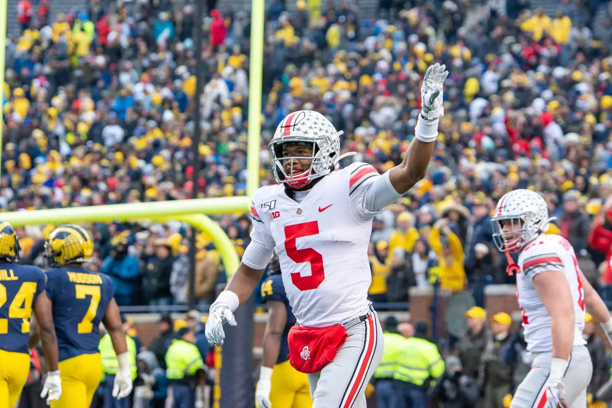 Garrett Wilson in a white number 5 Ohio State road jersey raising one arm in a packed Michigan Stadium