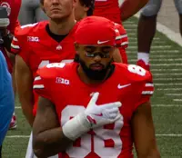 Gee Scott Jr. in a scarlet number 88 Ohio State jersey standing with teammates on the sideline