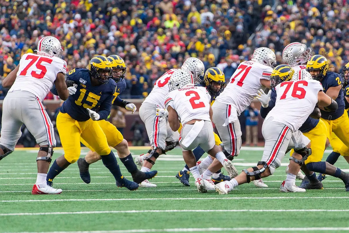 Ohio State running back J.K. Dobbins, number 2 in road white, running low behind his offensive linemen as Michigan defenders converge