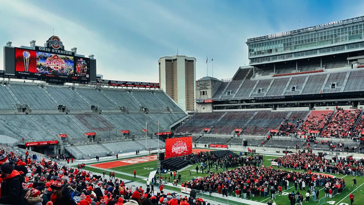 Inside Ohio Stadium on a grey winter day, a crowd in scarlet gathered on the field and in the lower stands, the south end scoreboard reading National Champions