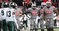 Ohio State linemen in grey uniforms standing near the line of scrimmage across from Michigan State players in white and green at Ohio Stadium