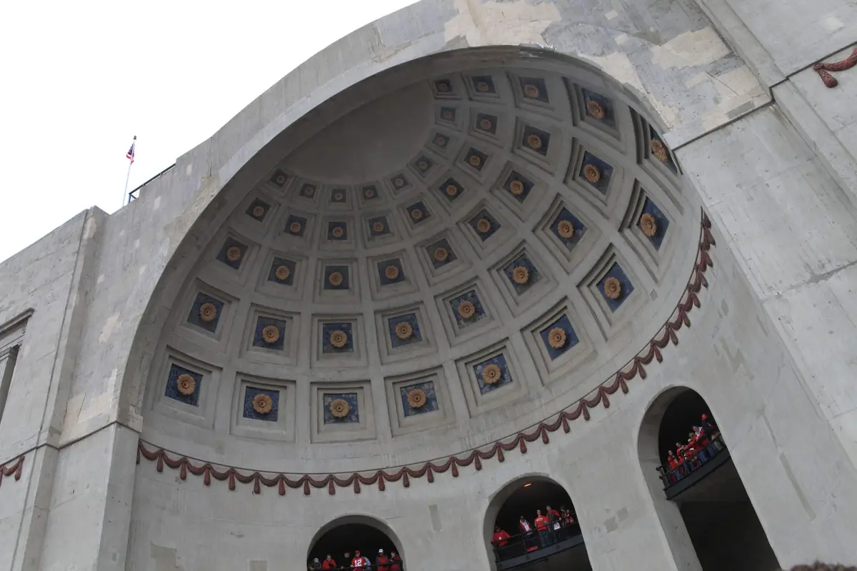The rotunda facade at Ohio Stadium seen from below, with fans standing in the arched openings