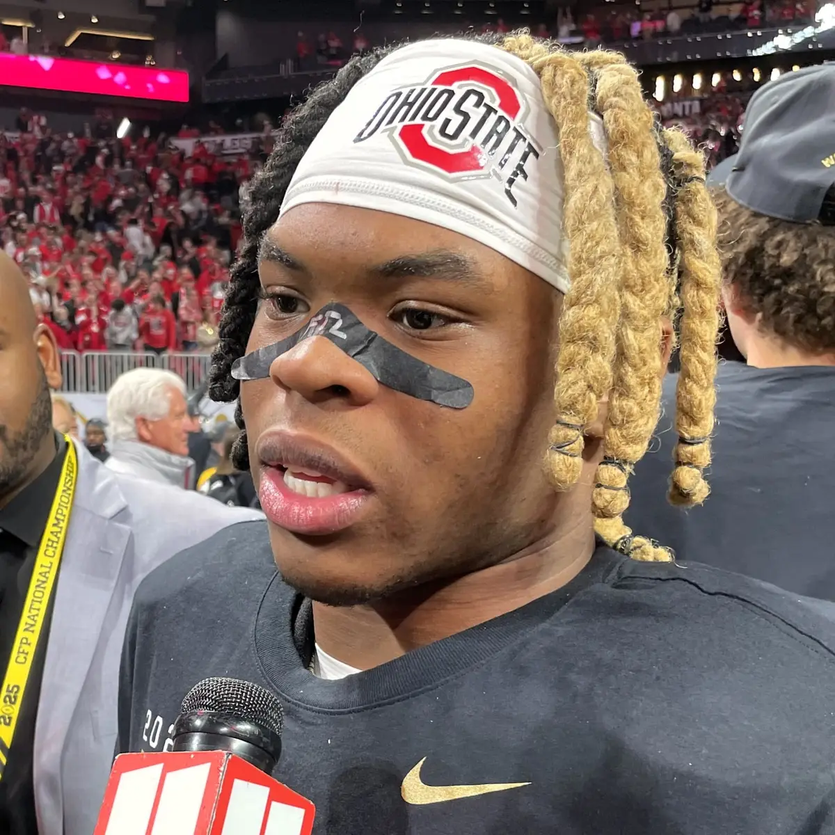 Quinshon Judkins in an Ohio State headband and eye black speaking into a microphone on the field after the national championship game