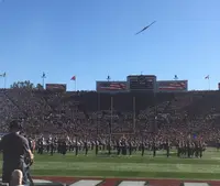 A B-2 bomber flies over the Rose Bowl as the marching bands stand on the field