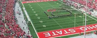 The Ohio State University Marching Band spelling out Script Ohio in white across the green field at Ohio Stadium, between the scarlet BUCKEYES and OHIO STATE end zones