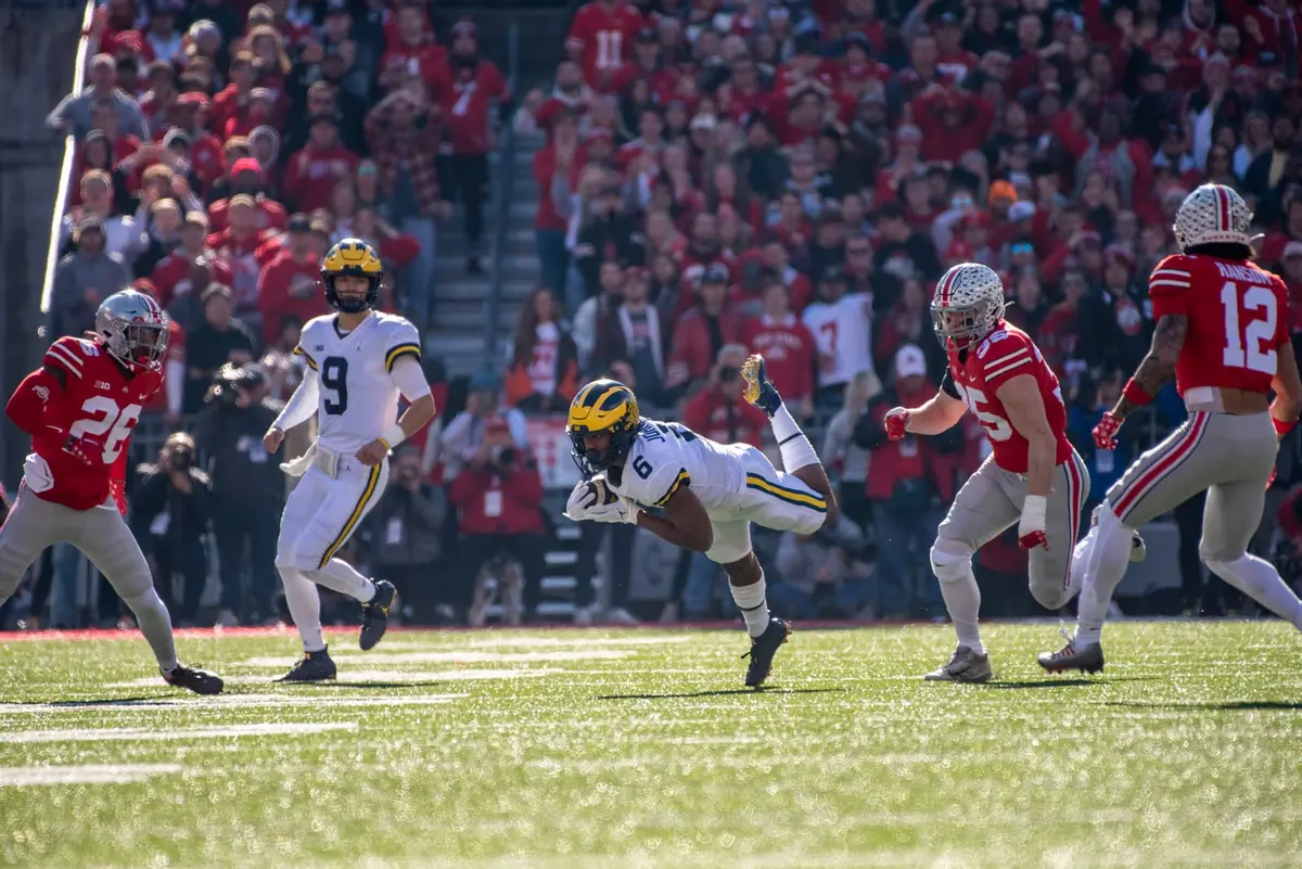 Ohio State linebacker Tommy Eichenberg in scarlet running toward a Michigan receiver who is diving forward with the ball