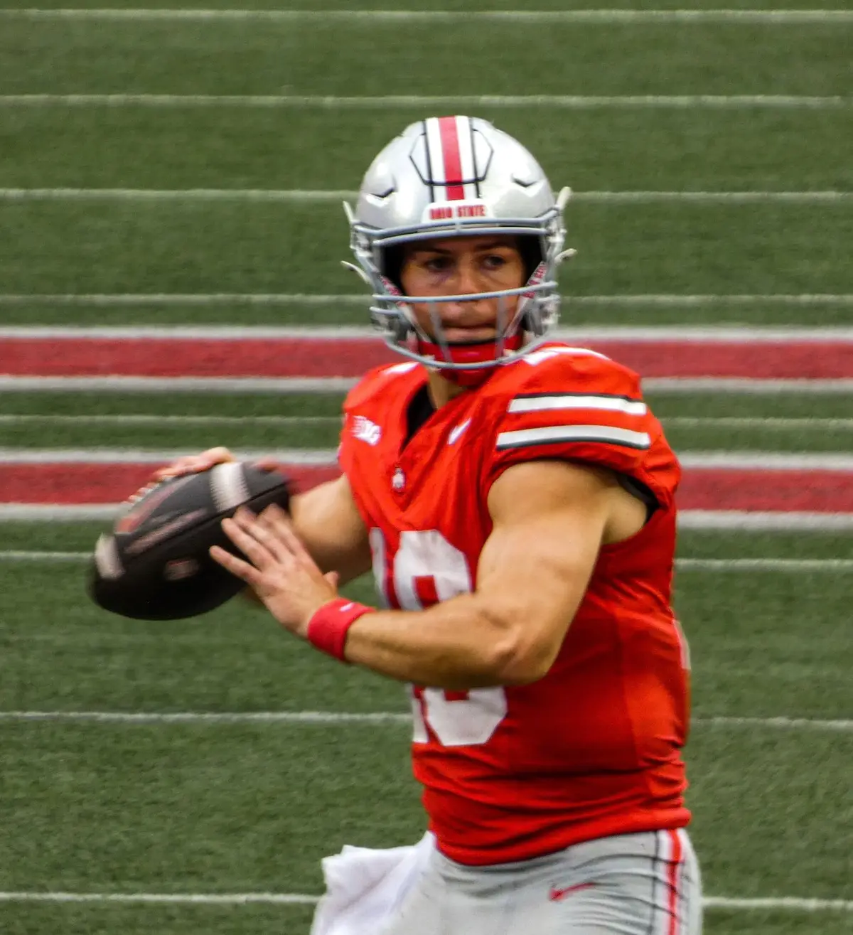 Will Howard in a scarlet Ohio State jersey cocking his arm to throw with an empty Ohio Stadium behind him